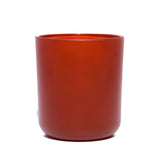 This image shows a cylindrical opaque glass candle container in a burnt orange color.