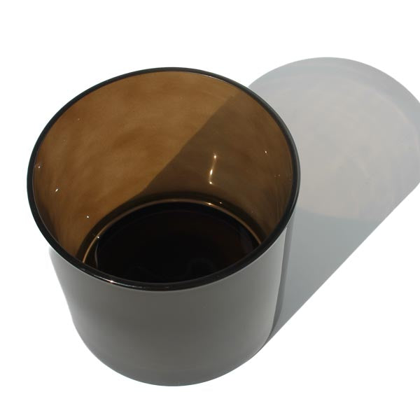 This image shows a cylindrical translucent glass candle vessel in a dark brown color.