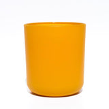 This image shows a cylindrical opaque  glass candle container in a golden yellow color.