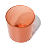 This image shows a cylindrical translucent  glass candle container in a peach color.