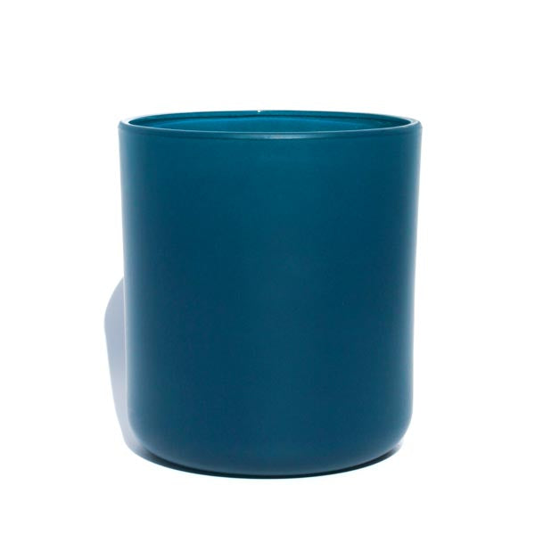 This image shows a cylindrical translation  glass candle container in a peacock blue color.