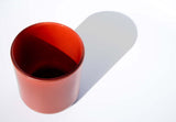 This image shows a cylindrical opaque glass candle vessel in a burnt orange color.