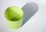 This image shows a cylindrical translucent glass candle container in a bright yellow-green color.