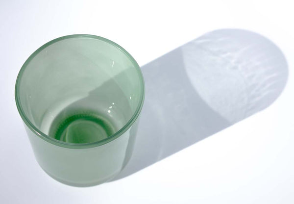 This image shows a cylindrical translucent  glass candle vessel in a jade green color.