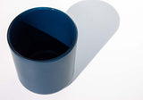 This image shows a cylindrical opaque  glass candle vessel in a navy blue color.