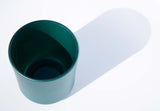 This image shows a cylindrical opaque  glass candle vessel in a metallic green color.